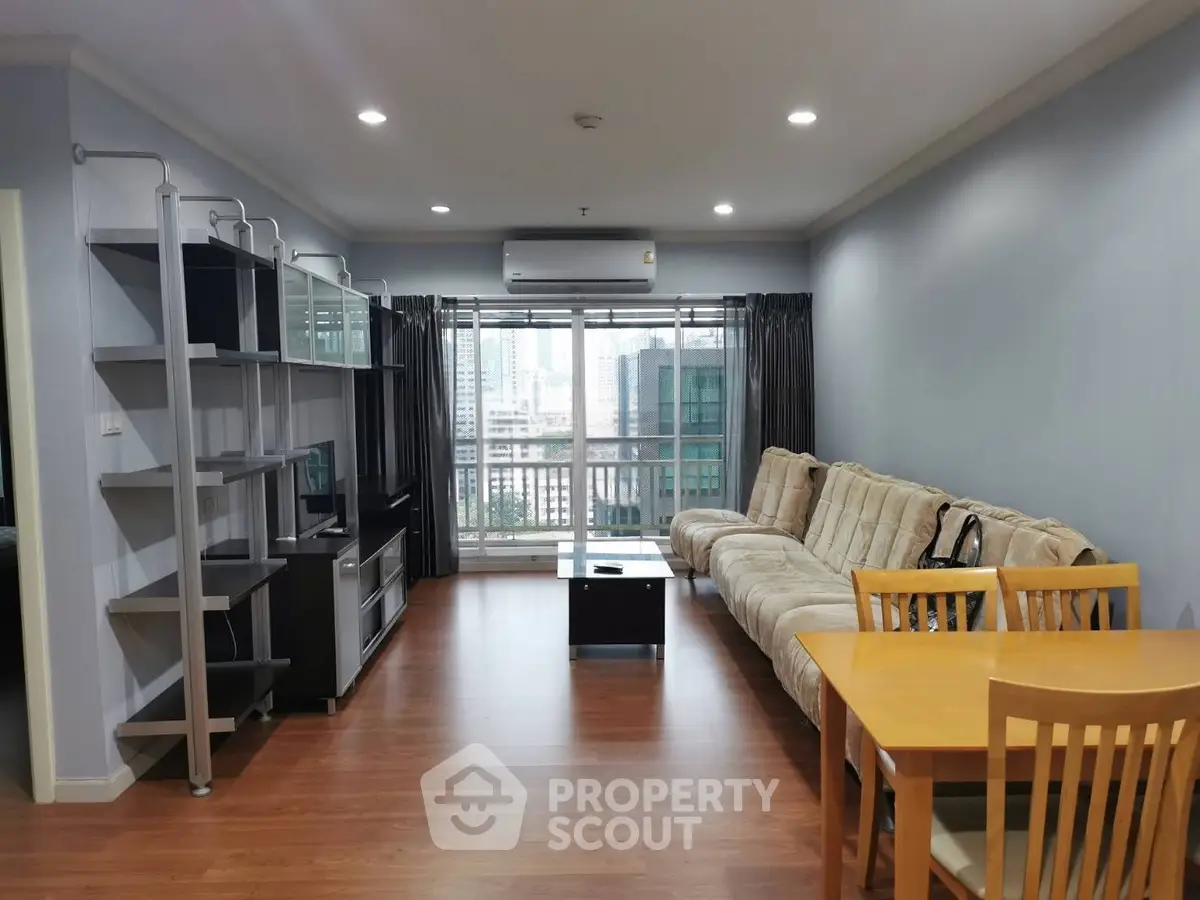 Spacious living room with modern decor and city view, featuring a cozy sofa and dining area.