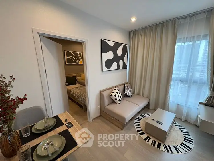 Modern living room with stylish decor and cozy seating area, adjacent to a chic bedroom.