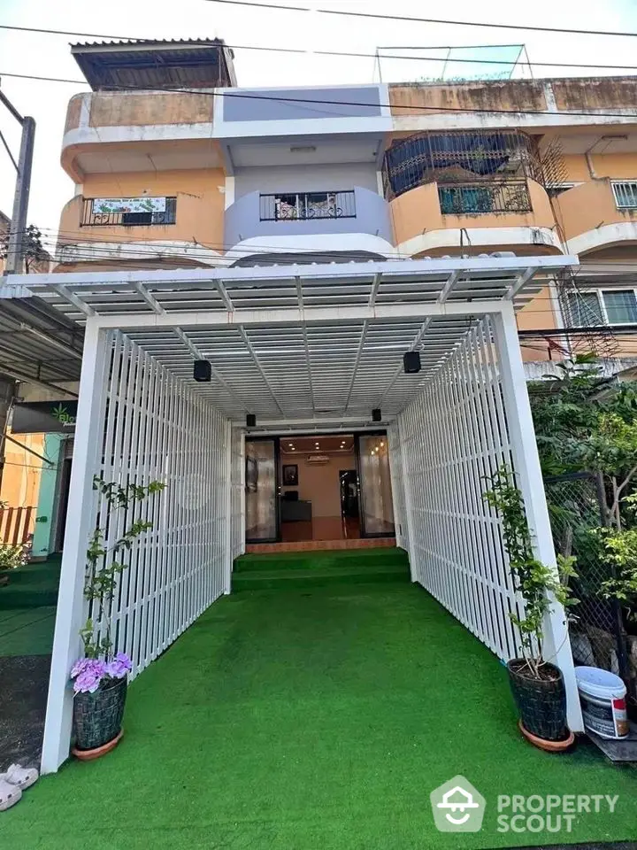 Charming townhouse with covered entrance and lush green artificial turf