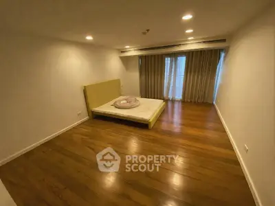 Spacious bedroom with wooden flooring and large windows for natural light.