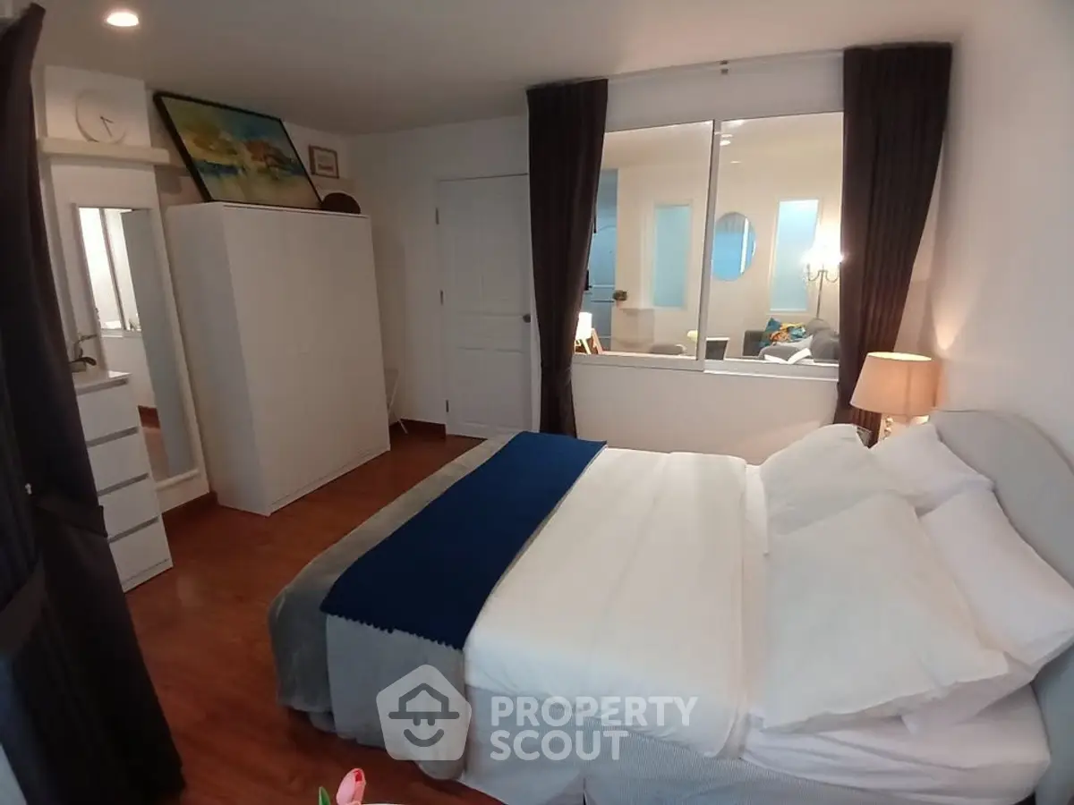 Cozy bedroom with modern decor and large window overlooking living area, perfect for relaxation.