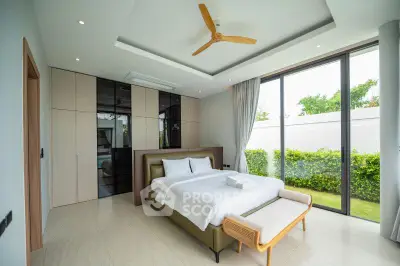 Luxurious bedroom with large windows and garden view, featuring modern decor and elegant furnishings.