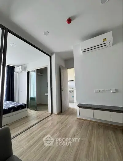 Modern apartment interior with sleek design, featuring a bedroom and living area with wooden flooring and air conditioning.