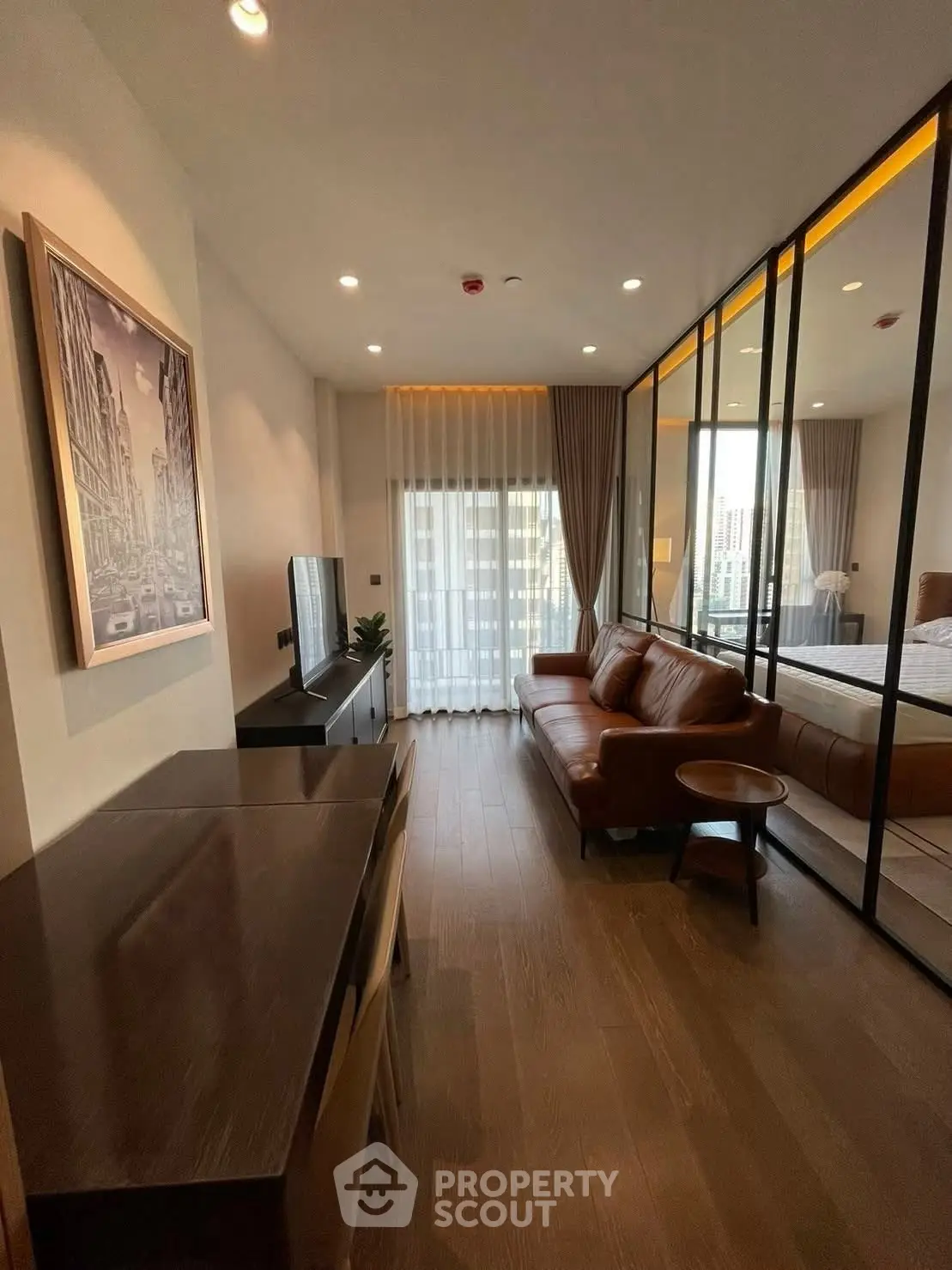 Modern living room with leather sofa and city view, featuring floor-to-ceiling windows and elegant decor.
