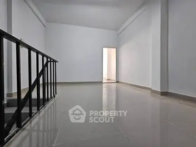 Spacious minimalist interior with sleek tiled flooring and open doorway, ideal for modern living.