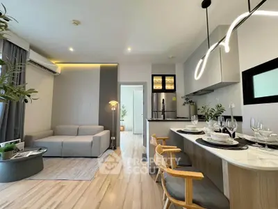 Modern open-layout living room and kitchen with stylish lighting and wooden flooring.
