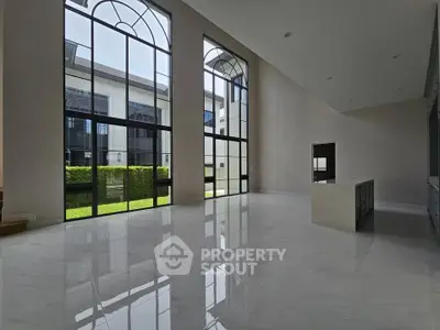 Spacious modern living room with high ceilings and large windows offering abundant natural light.