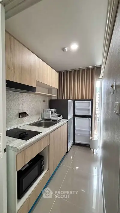 Modern compact kitchen with sleek appliances and stylish cabinetry in a contemporary apartment.