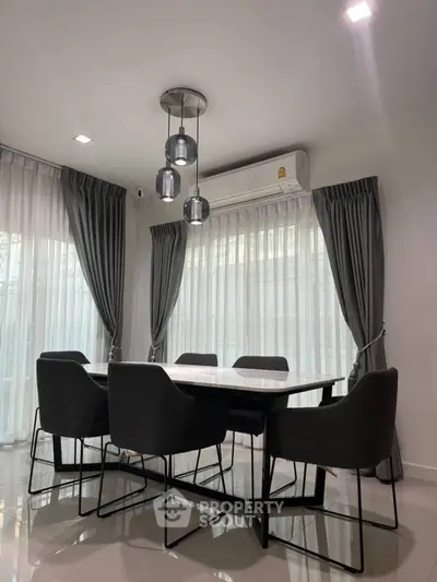 Modern dining area with sleek table, elegant chairs, and stylish pendant lighting.