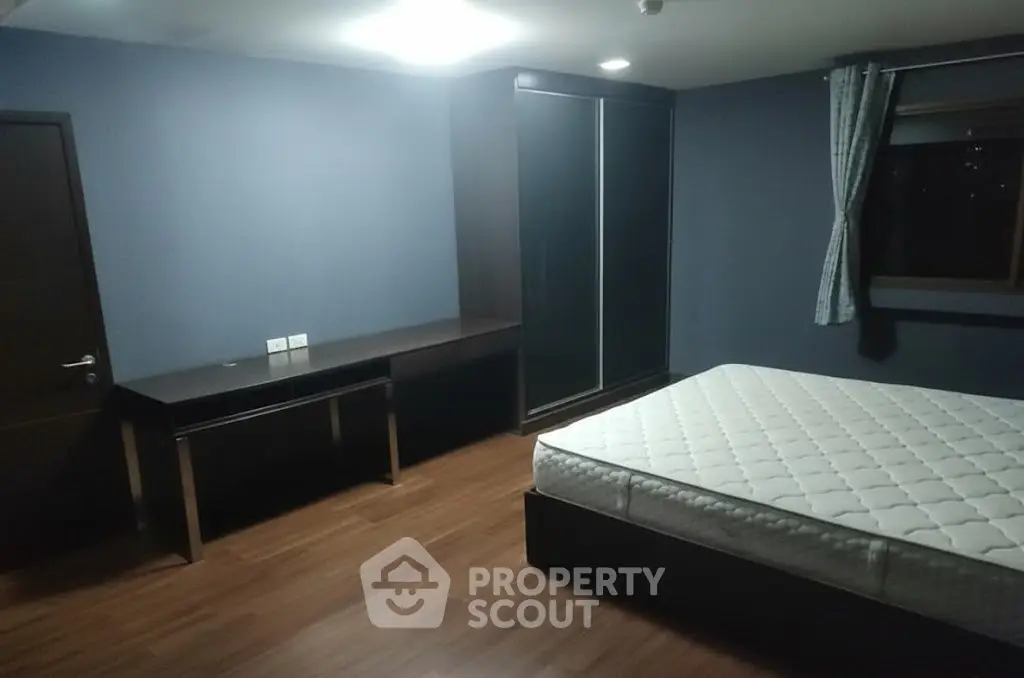 Spacious bedroom with modern furnishings and large window for natural light.