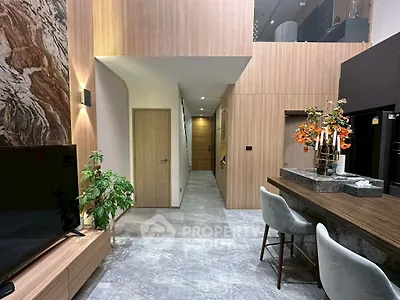 Modern living room with stylish decor and open layout, featuring a sleek TV unit and elegant bar seating.