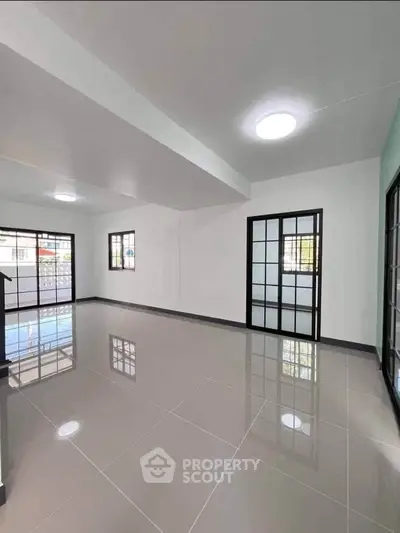 Spacious modern living room with glossy tiled floors and large windows for natural light.