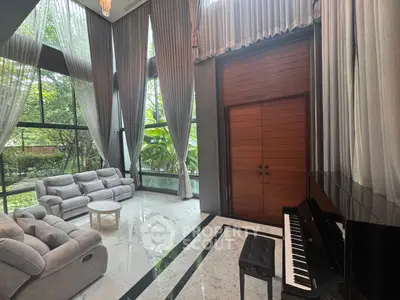 Luxurious living room with high ceilings, large windows, and elegant piano, offering a serene garden view.