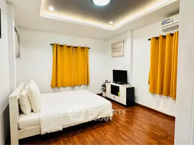 Cozy bedroom with wooden flooring and bright yellow curtains
