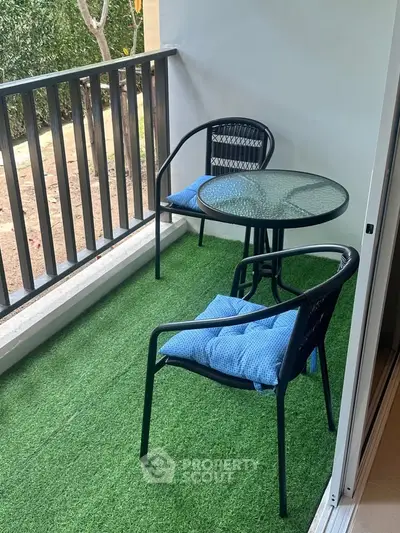 Charming balcony with artificial grass and cozy seating, perfect for relaxation.