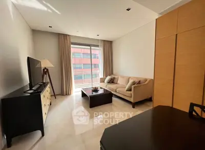 Modern living room with cozy sofa, flat-screen TV, and large window offering natural light.