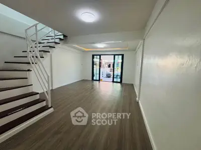 Spacious modern living room with wooden flooring and staircase, perfect for family gatherings.