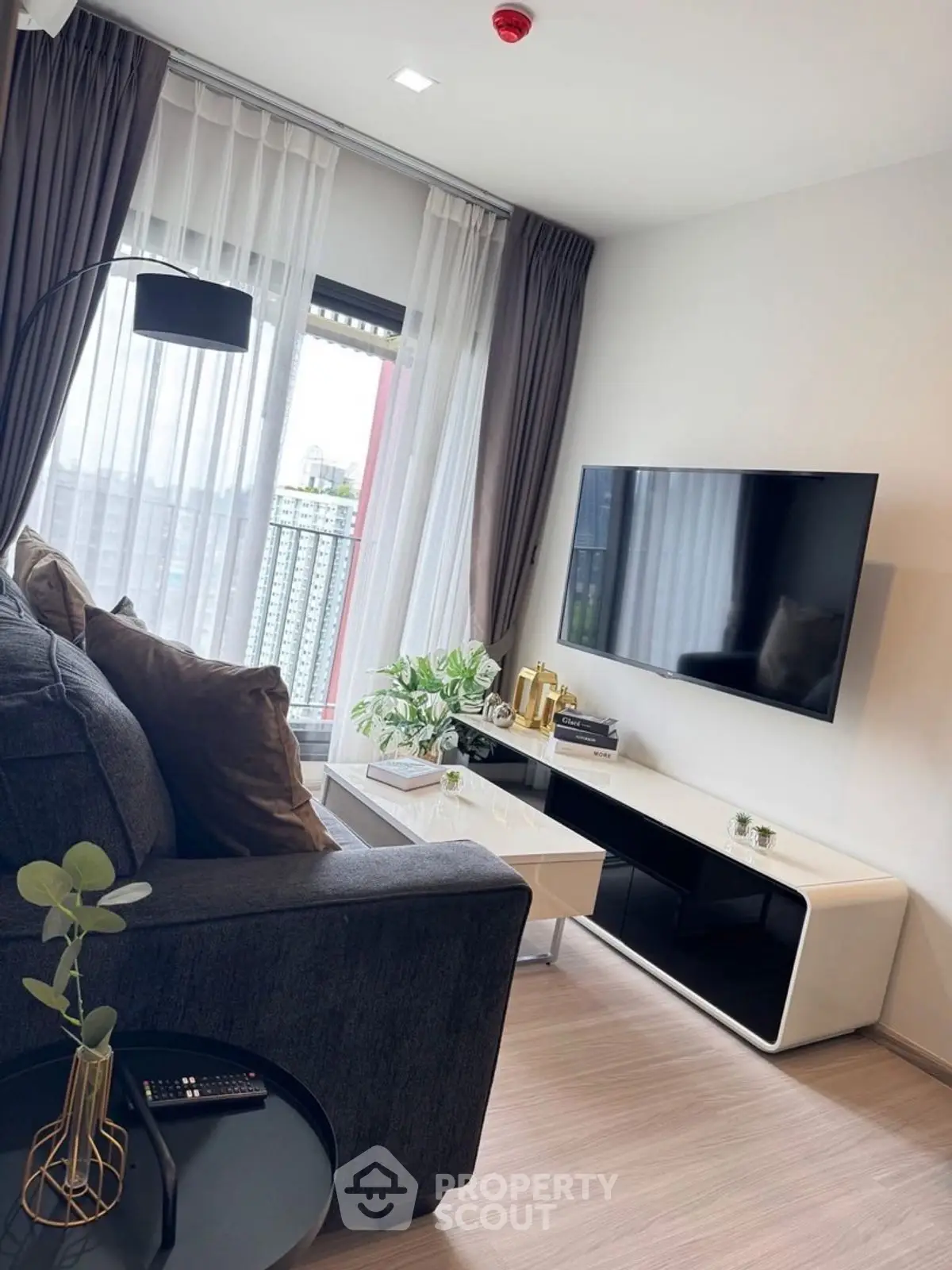 Modern living room with sleek furniture and large TV, featuring floor-to-ceiling windows and stylish decor.