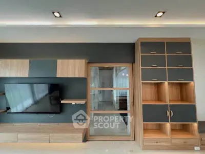 Modern living room with sleek wooden cabinetry and mounted TV, showcasing contemporary design.