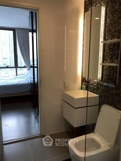 Modern bathroom with sleek design and city view from adjacent bedroom.