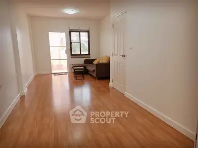 Spacious living room with wooden flooring and natural light, perfect for relaxation and entertaining.