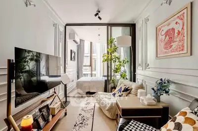 Stylish living room with modern decor and a view into a cozy bedroom, featuring elegant furnishings and art.