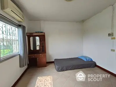 Minimalist bedroom with single bed and vanity, featuring air conditioning and natural light.