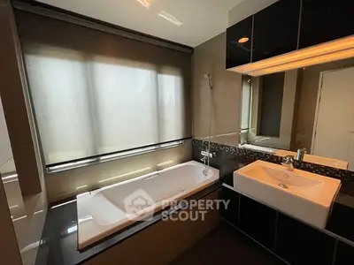 Modern bathroom with sleek design, featuring a bathtub and stylish sink area.