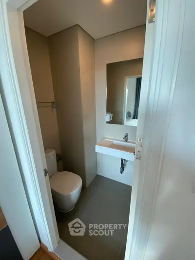 Modern bathroom with sleek design and compact layout, featuring a toilet and sink.