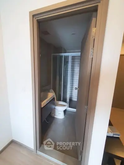 Modern bathroom with glass shower and sleek vanity in contemporary apartment.