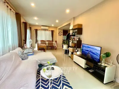 Spacious living room with modern decor and natural light, featuring a cozy seating area and entertainment setup.