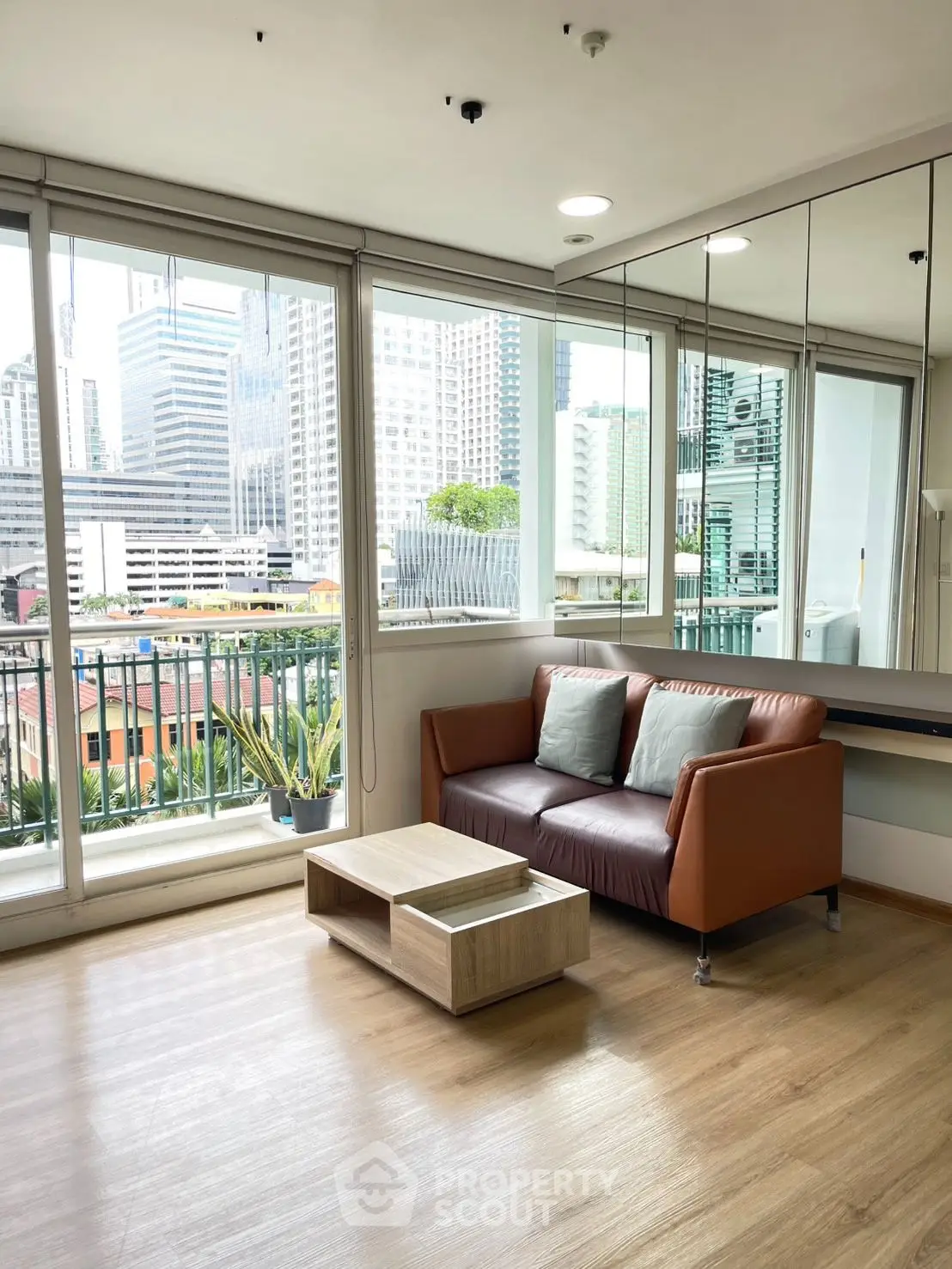 Modern living room with city view, featuring large windows and stylish furniture.