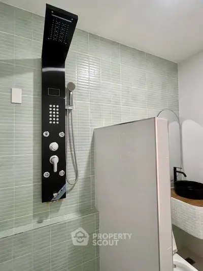 Modern bathroom with sleek shower panel and stylish basin in contemporary design.