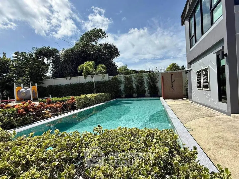 Luxurious outdoor pool area with lush greenery and modern architecture, perfect for relaxation.