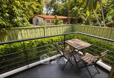 Charming balcony with lush garden view and cozy seating area, perfect for relaxation.