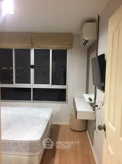 Cozy bedroom with city view, featuring a wall-mounted TV and air conditioning for comfort.