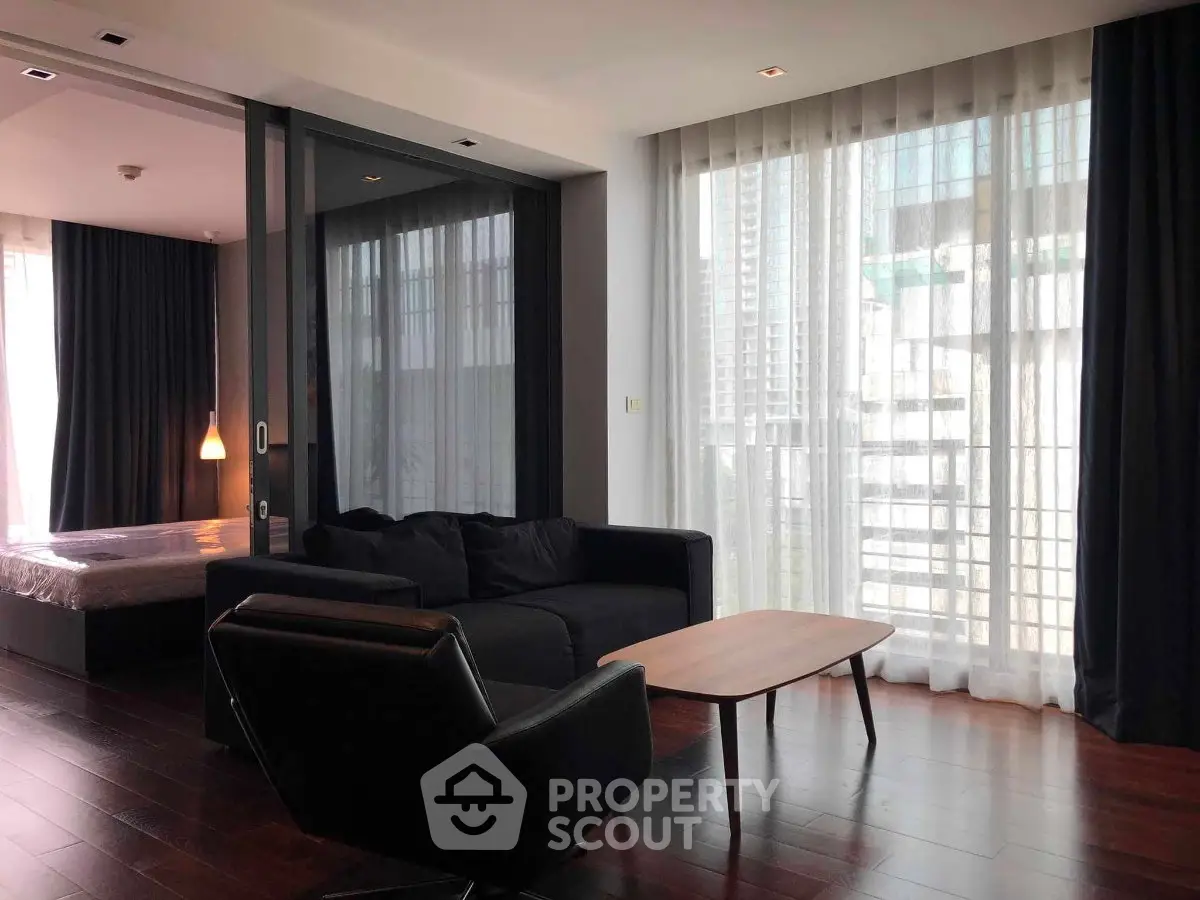 Modern living room with floor-to-ceiling windows and sleek furniture in a high-rise apartment.