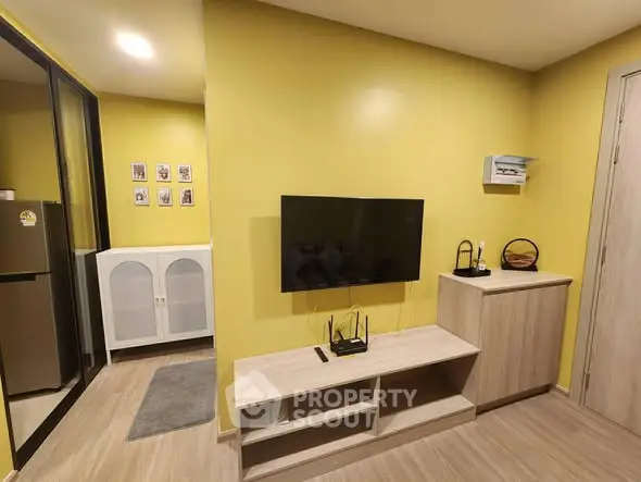 Modern living room with yellow walls, wall-mounted TV, and sleek storage units.