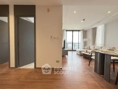Spacious modern living room with wooden flooring and large windows offering natural light.