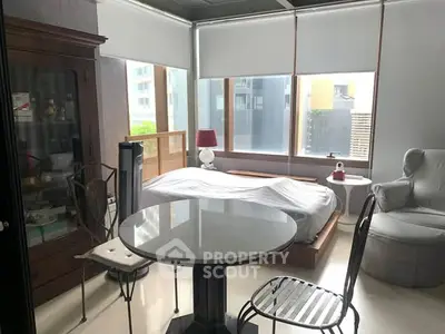 Cozy bedroom with large windows and stylish furniture in a modern apartment.
