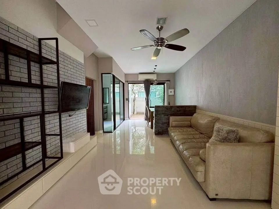 Modern living room with sleek design and open layout, featuring a ceiling fan and stylish decor.