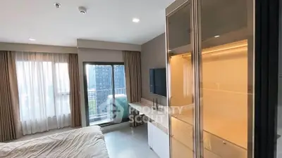 Modern bedroom with balcony and city view, featuring sleek furniture and natural light.