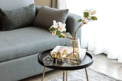 Stylish living room with modern gray sofa and elegant decor on round coffee table.