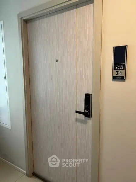 Modern apartment entrance with secure electronic lock and room number display.