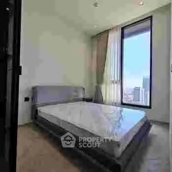 Modern bedroom with large window offering city view and natural light.