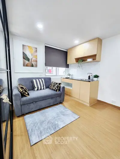 Modern compact living room with cozy sofa and stylish kitchenette in open layout apartment.