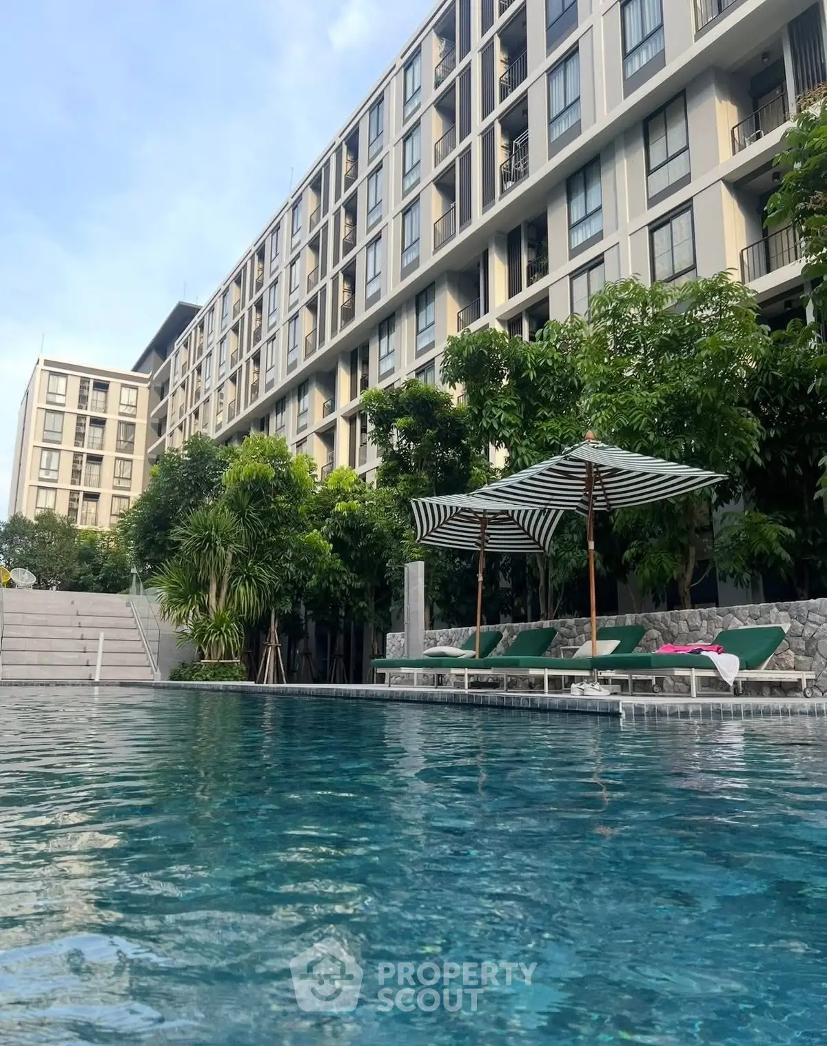 Luxurious apartment complex with stunning pool and lush greenery, perfect for modern living.