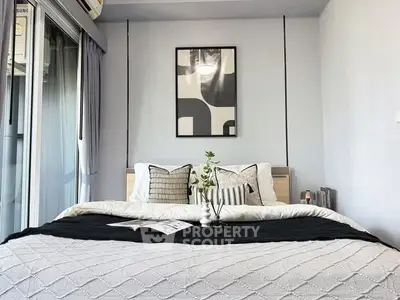 Modern bedroom with stylish decor and natural light, featuring a cozy bed and elegant wall art.