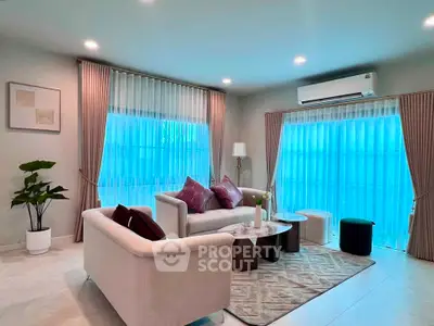 Elegant living room with modern furniture and large windows, featuring stylish decor and ambient lighting.