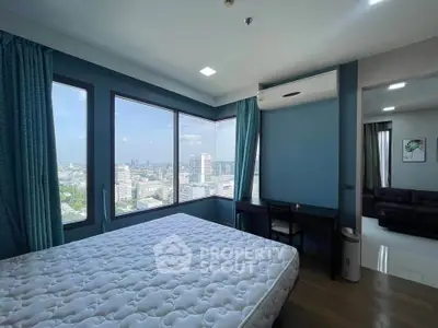 Spacious bedroom with panoramic city view and modern furnishings in high-rise apartment.